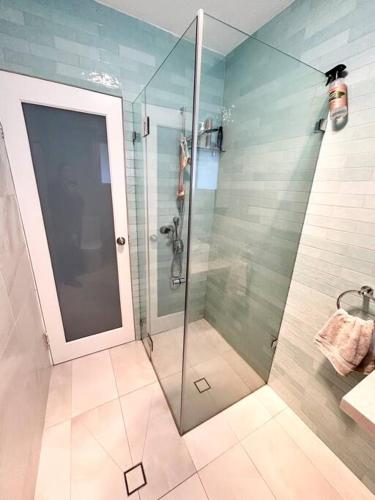 a shower with a glass door in a bathroom at One bedroom apartment and CARPORT close to beaches, airport,CBD in Sydney