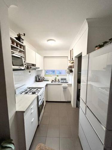 a white kitchen with a stove and a sink at entire flat, quiet, close to:beaches, airport, CBD in Sydney