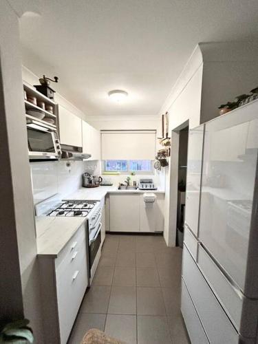 a white kitchen with a stove and a sink at One bedroom apartment and CARPORT close to beaches, airport,CBD in Sydney
