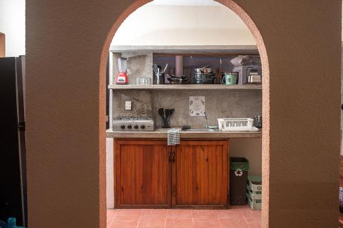 a kitchen with an archway with a stove and a sink at Mapache Hostel & Camping in Holbox Island