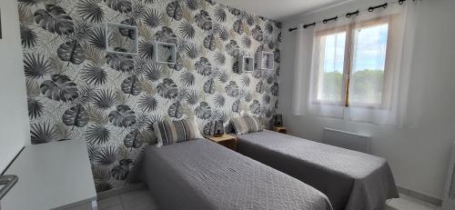 - une chambre avec 2 lits et un mur recouvert de papier peint dans l'établissement La Catalane - Les Jardins du Rivage - wifi- piscine, au Barcarès