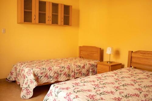 2 camas en un dormitorio con paredes amarillas en Amplia Casa de Campo con Piscina en Cieneguilla, en Cieneguilla