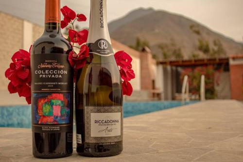 two bottles of wine sitting on a table with flowers at Amplia Casa de Campo con Piscina en Cieneguilla in Cieneguilla
