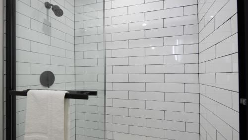 a white tiled shower with a towel on a rack at The Catrina Hotel in San Mateo