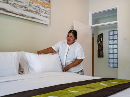 a woman is standing next to a bed at Alinta Villa 1 in Sanur