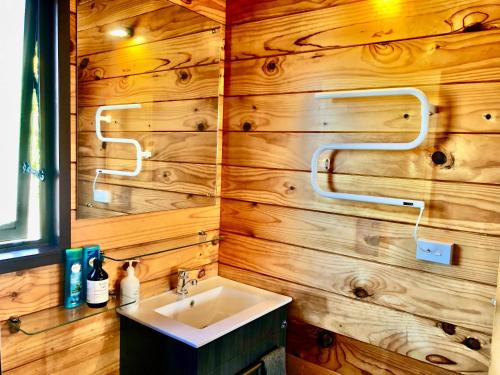 a bathroom with a sink and a wooden wall at The Mountain Stable Studio in Rangataua