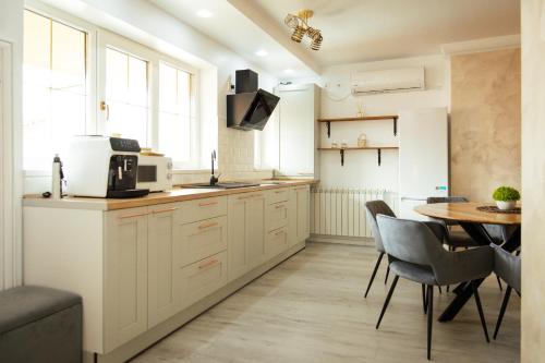 a kitchen with white cabinets and a table with chairs at Kasa Nouveau in Oradea