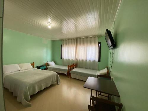 a bedroom with a bed and a couch and a television at Pousada355 in Passo Fundo