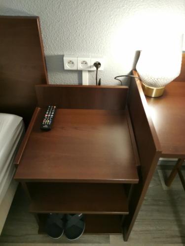 a nightstand with a remote control on it next to a bed at Appart Hotel La Defense in Courbevoie