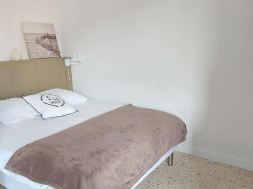 ein Bett mit einer Decke auf dem Zimmer in der Unterkunft Le Moth Marseillan in Marseillan