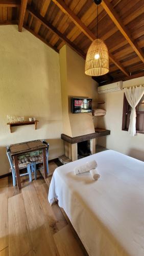 a bedroom with a white bed and a table at Pousada Capitão Cook in Praia do Rosa