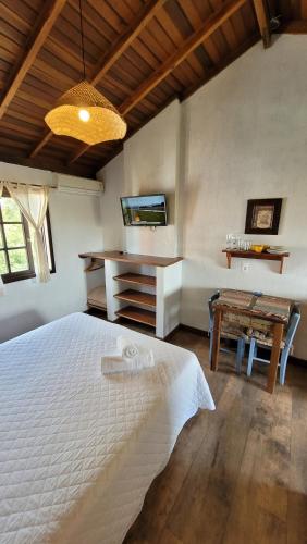 a bedroom with a white bed and a desk at Pousada Capitão Cook in Praia do Rosa