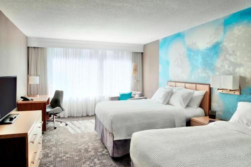 a hotel room with two beds and a desk at Courtyard by Marriott Toronto Downtown in Toronto