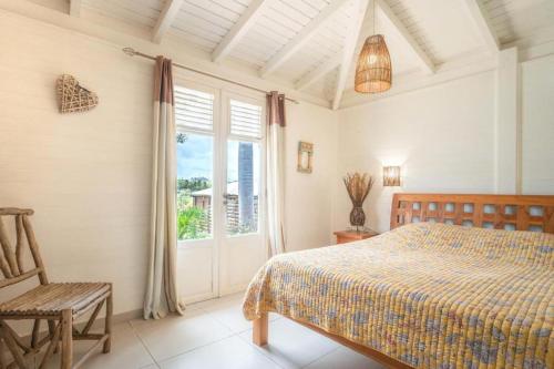 een slaapkamer met een bed, een stoel en een raam bij Villa Tikitanga avec piscine 10X5m à 650m de la mer in Saint-François