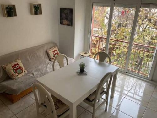 een woonkamer met een witte tafel en stoelen en een bank bij Appartement à Roses centre in Roses
