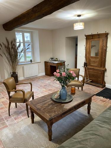 a living room with a table with flowers on it at Gîte du fournil « Chez Nicole » in Ully-Saint-Georges