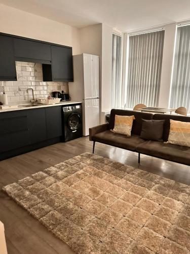 a living room with a couch and a kitchen at Stylish 1 & 2 Bed Apartment - Desborough - Kettering - Sleeps up to 5 - Free Parking, - WIFI - Contractors, Professionals, Families and Relocators - By The Home Makers Hub in Kettering