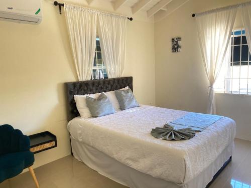 um quarto com uma cama com lençóis brancos e 2 janelas em Sir Frederick's Villa em Florence Hall