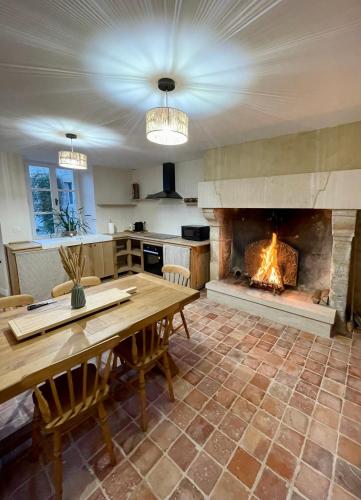 a kitchen with a table and a fireplace at Gîte du fournil « Chez Nicole » in Ully-Saint-Georges
