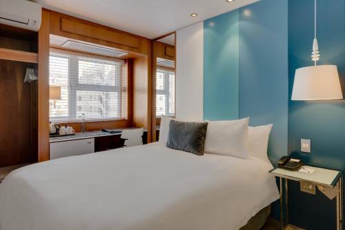 1 dormitorio con cama blanca y pared azul en Protea Hotel by Marriott Cape Town Sea Point, en Ciudad del Cabo