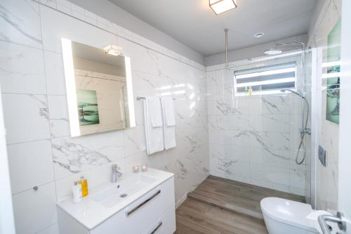 La salle de bains blanche est pourvue d'un lavabo et d'une douche. dans l'établissement Guesthouse Keflavik by Reykjavik Keflavik Airport, à Keflavík