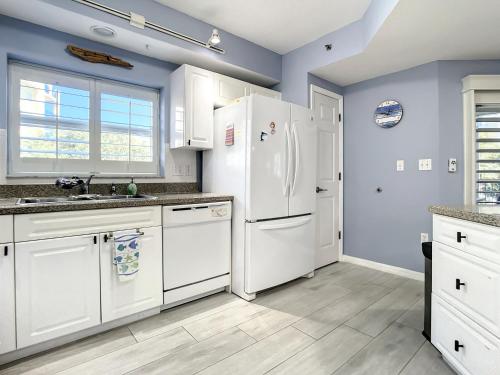 een keuken met witte apparatuur en blauwe muren bij Oceanwalk Jr. Penthouse ~ Across from pool tennis shuffleboard ~ Walk to beach OW7-207 in New Smyrna Beach