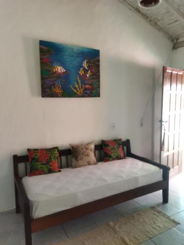 a bed in a room with a painting on the wall at Casa da Drica Trancoso in Trancoso