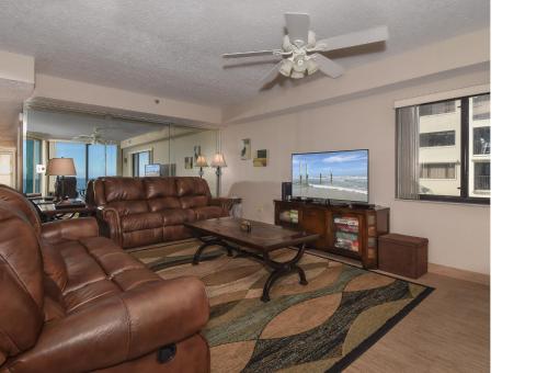a living room with brown leather furniture and a flat screen tv at Floor-to-Ceiling Oceanfront Views ~ Chadham-by-the-Sea 315 in New Smyrna Beach