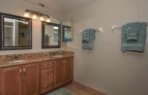 a bathroom with two sinks and two mirrors at Floor-to-Ceiling Oceanfront Views ~ Chadham-by-the-Sea 315 in New Smyrna Beach