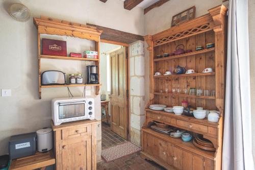 - une cuisine avec des placards en bois et un four micro-ondes dans l'établissement Domaine Moulin de Boiscorde, à Rémalard