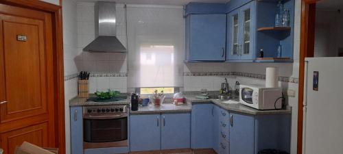 a small kitchen with blue cabinets and a microwave at Un rincón en barraña in Boiro