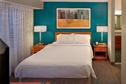 Residence Inn Hartford Avon في Avon: غرفة نوم بسرير كبير بجدران زرقاء
