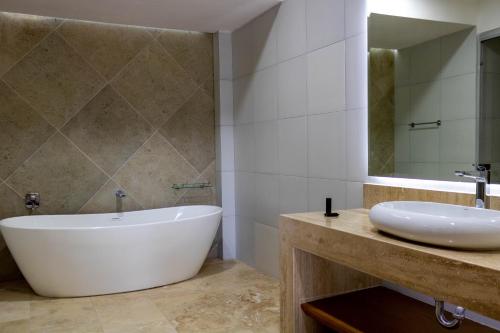 a bathroom with a tub and a sink and a mirror at Hotel 5 Inn Select in Rancho de la Cruz