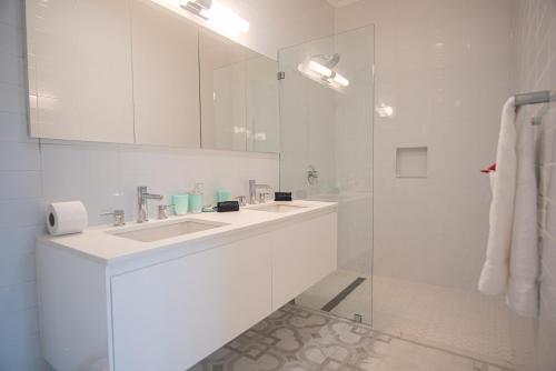 uma casa de banho branca com um lavatório e um espelho em The Cove - Condo Hotel - Palm Beach Strip em Palm Beach