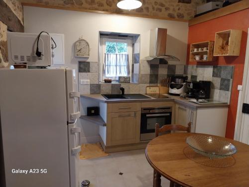 a kitchen with a table and a refrigerator at Le Petit Chapître in Villajou