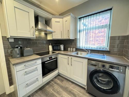 eine Küche mit weißen Schränken und einer Waschmaschine in der Unterkunft Seaviews Apartment 2, Whitley Bay Sea Front in Whitley Bay