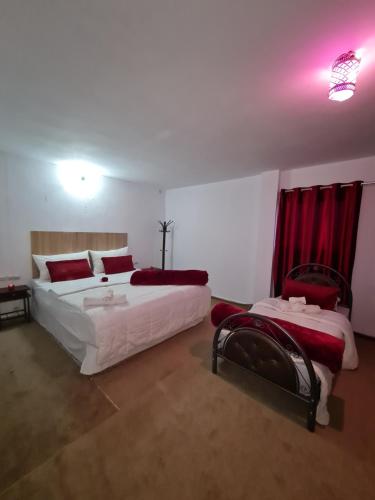 a bedroom with two beds with red curtains at Hôtel et Restaurant ARIJ in Midelt