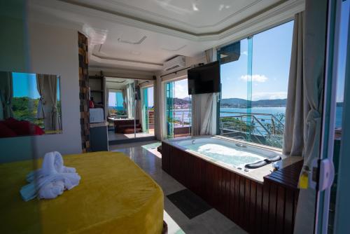 a bedroom with a tub with a view of the ocean at Pousada Mirante do César in Bombinhas