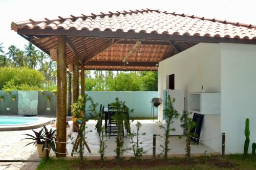 a patio with a wooden pergola next to a pool at Vila Las Hermanas in Pôrto de Pedras