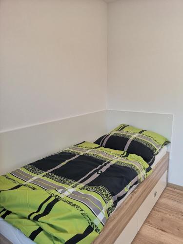 a bed with a green and black comforter and two pillows at Modern flat, WIFI, central, calm, clean in Ingolstadt