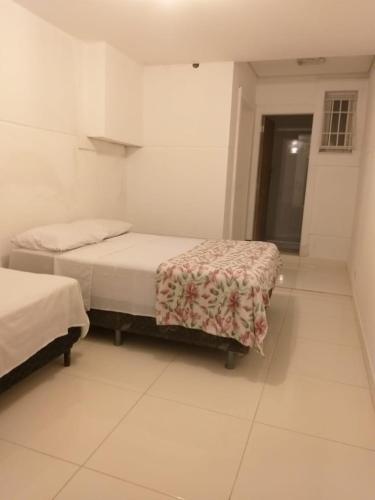 two beds in a room with white walls at CARIBONI in Guarujá