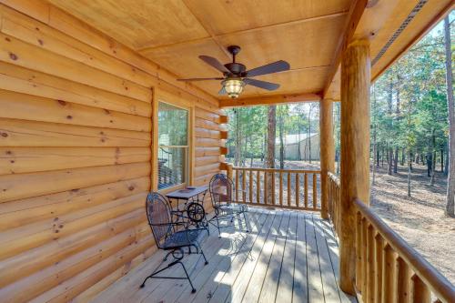 a log cabin with a ceiling fan and chairs on a porch at Tumbling Shoals Cabin with Fire Pit 1 Mi to Lake in Heber Springs