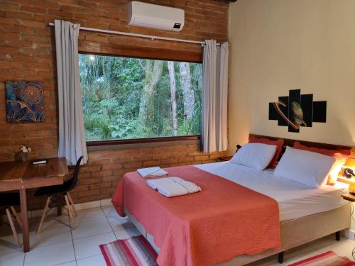 a bedroom with a bed and a desk and a window at Contempla Joanópolis in Joanópolis