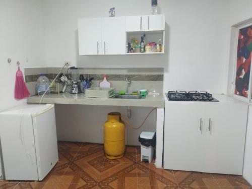 a kitchen with white cabinets and a yellow trash can at Mini Suite in Manta