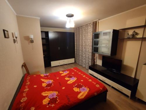 1 dormitorio con cama roja y TV de pantalla plana en Admiral Home en Mykolaiv