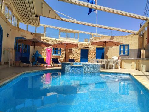a large swimming pool with umbrellas in a building at Margerita Farmhouse in Qrendi