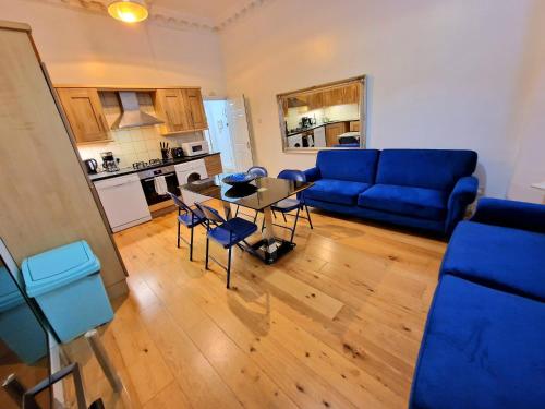 a living room with a blue couch and a table at Lovely Ground Floor Home with Private Garden by Earls Court Station in London