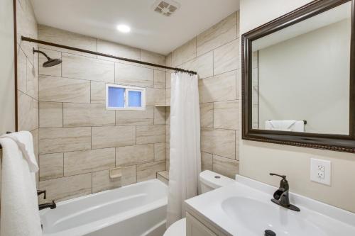 a bathroom with a white tub and a sink and a mirror at Stylish Logan Retreat with Smart TV and Central A and C! in Logan