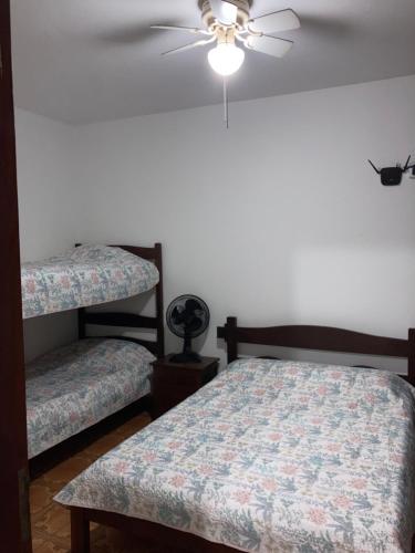 a bedroom with two beds and a ceiling fan at Apartamentos Petrópolis in Ubatuba