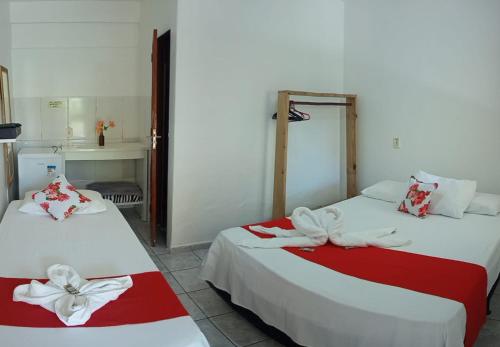 two beds with red and white sheets in a room at Pousada Recanto da Vila in Trancoso